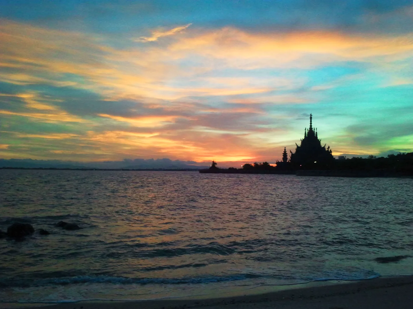 The Sanctuary of Truth silhouetted beside the sea beneath a colourful sky.